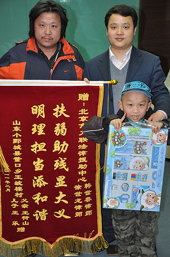 图为韩世春律师接受王乐父亲赠送的锦旗