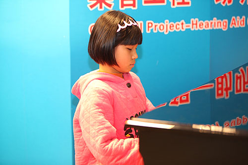 图为接受救助的李艺园小朋友在捐赠仪式上演奏钢琴