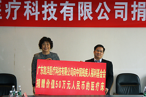 图为汤小泉理事长（左一）接受广东凯洋医疗科技 集团有限公司捐赠医疗床