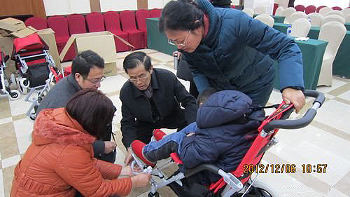 图为河北省残疾人福利基金会杨俊民理事长向残疾儿童家长讲解轮椅使用技巧、调节方法