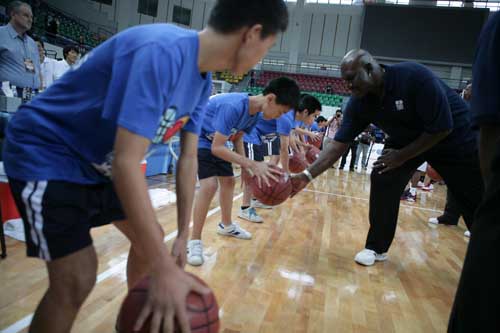 图为NBA传奇球星戴瑞尔·道金斯在活动中指导聋哑学生打球