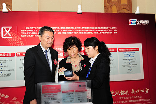 中国残疾人福利基金会理事长汤小泉（中）、中国银联董事长苏宁（左）体验POS终端捐款