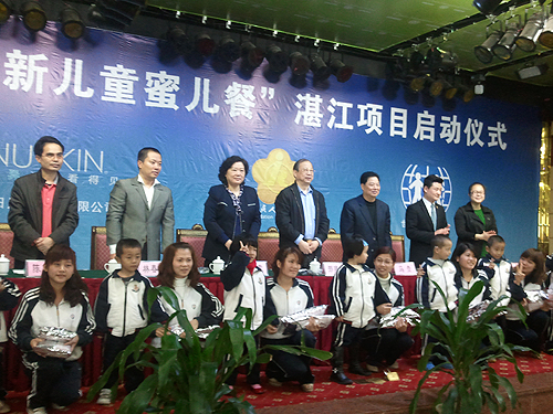 图为与会领导向贫困残疾儿童代表赠送蜜儿餐