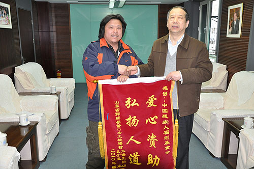图为邢建绪副理事长代表基金会接受王乐父亲赠送的锦旗