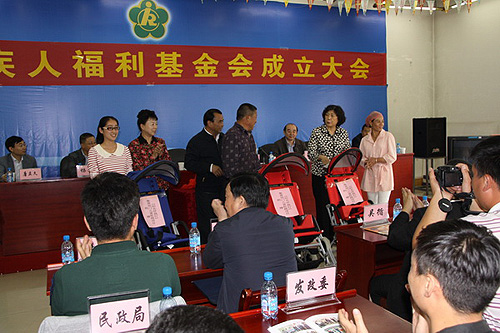 图为汤小泉理事长、阿布力孜·尼牙孜副政委、杨璞斌理事长向残疾儿童家属赠送了 台湾明门集团捐赠的脑瘫儿童轮椅