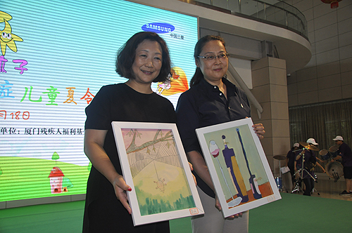 图为自闭症儿童向费薇副理事长和王幼燕总裁赠送绘画作品