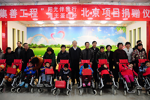 图为与会领导和嘉宾向残疾儿童代表发放儿童轮椅、蛋白粉