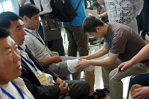 图为假肢公司工作人员为残疾人试穿和调试假肢