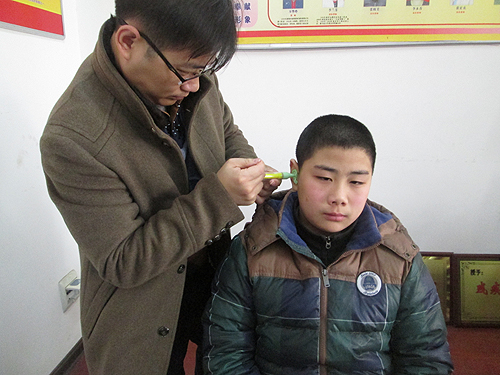 图为助听器公司专业检测人员为小雷进行助听器适配调试