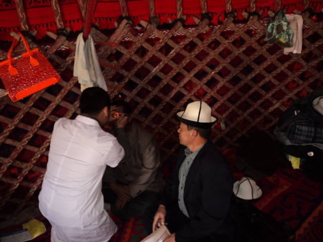 图为眼科医生在新疆牧场为白内障患者检查
