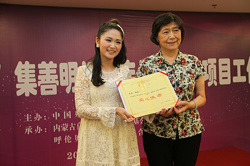 图为汤小泉理事长向李烁(娃娃)颁发“阳光伴我行”公益项目“爱心使者”证书