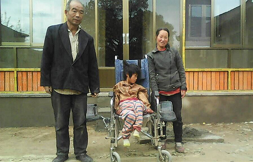 图为小奋与父亲、母亲在修缮后的房屋前合影